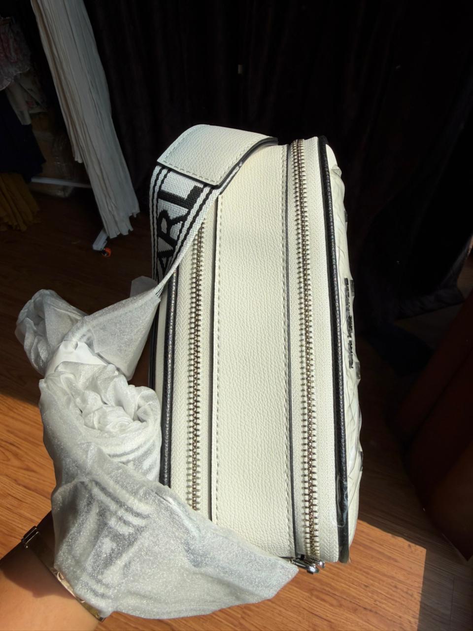 Karl Lagerfeld Paris Maybelle Camera Crossbody bag in white with black lettering.